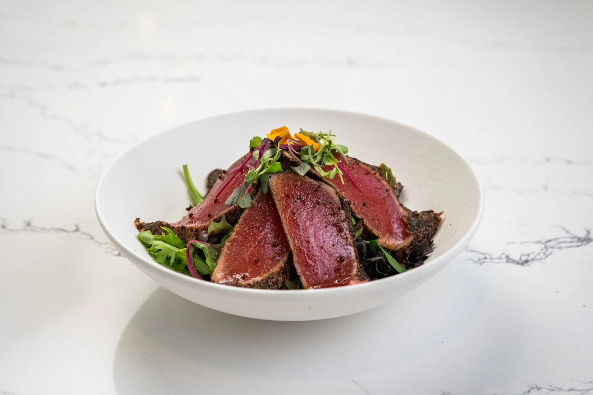 Seared tuna salad with mixed greens and edible flowers at Toki Ramen & Sushi, a Japanese Restaurant in Denver