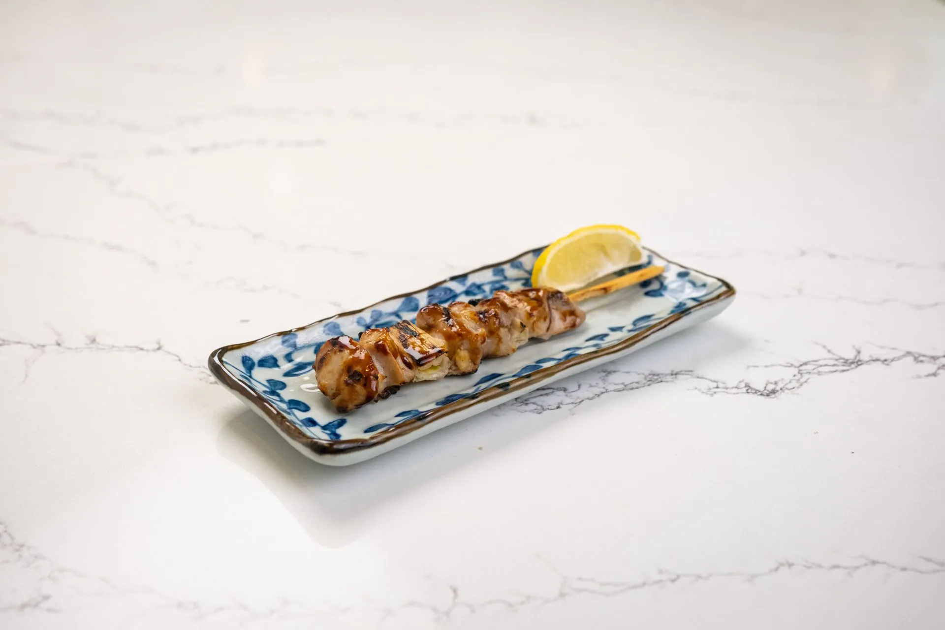 Grilled chicken skewer with teriyaki glaze and lemon at Toki Ramen & Sushi, a Japanese Restaurant in Denver