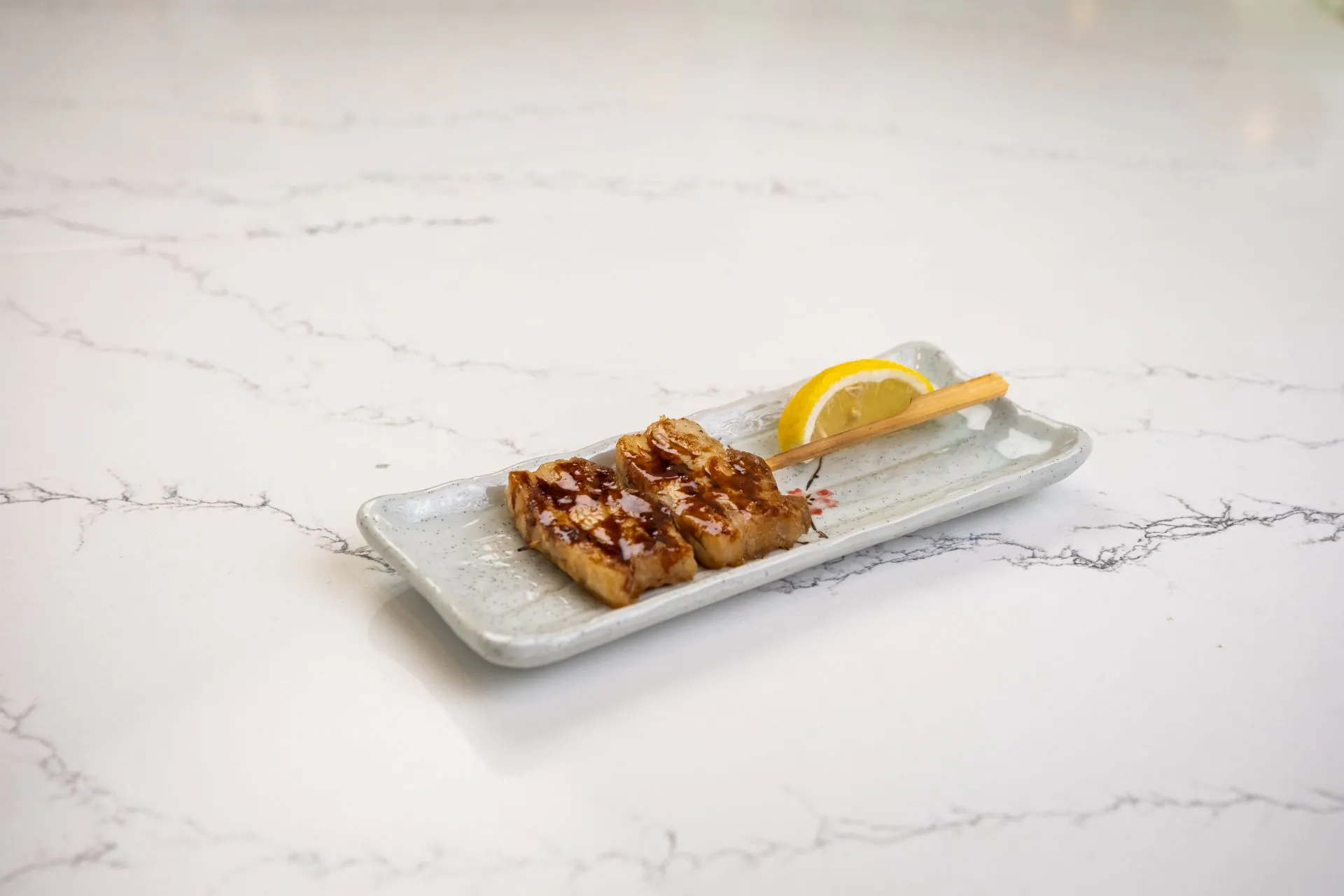 Grilled pork belly skewer with teriyaki glaze and lemon at Toki Ramen & Sushi, a Japanese Restaurant in Denver